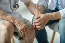 A senior client sits across from a professional counsellor during a geriatric counselling session, both engaged in thoughtful conversation.